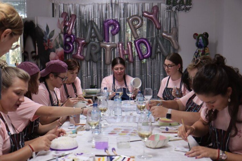 Un grupo de personas reunidas alrededor de una mesa con globos, platos y vasos. 3