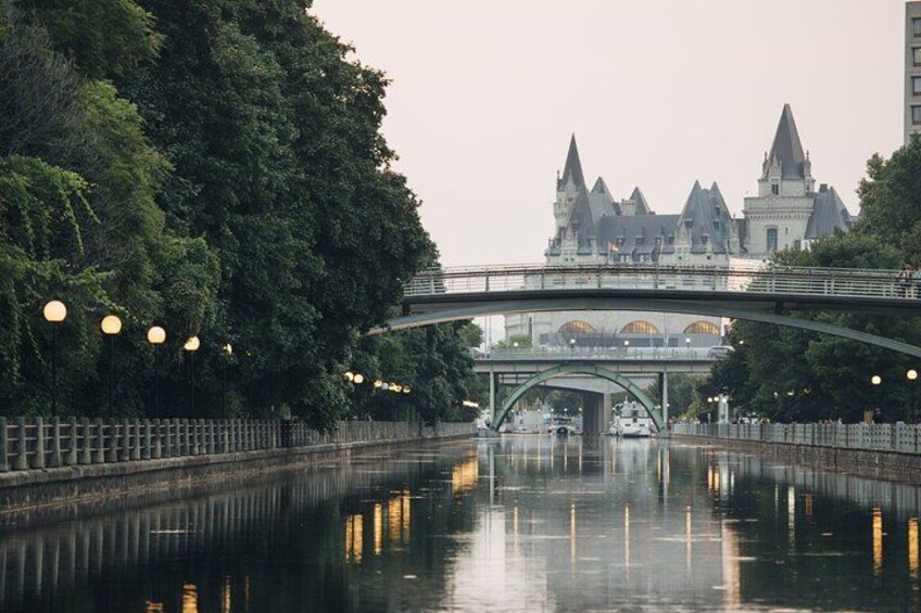 A river with a bridge, a castle-like building in the background, and trees along the riverbank. 2