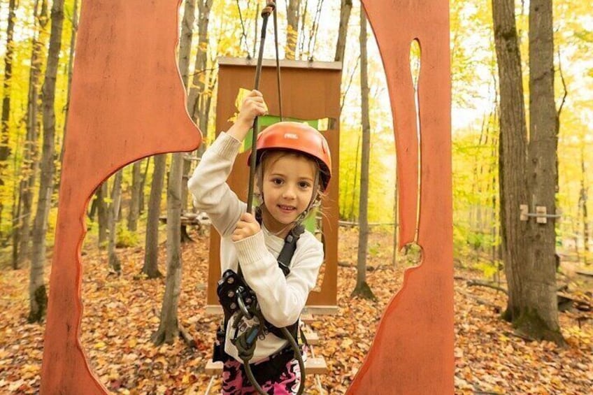 A person in a forest with a zip line structure. 5