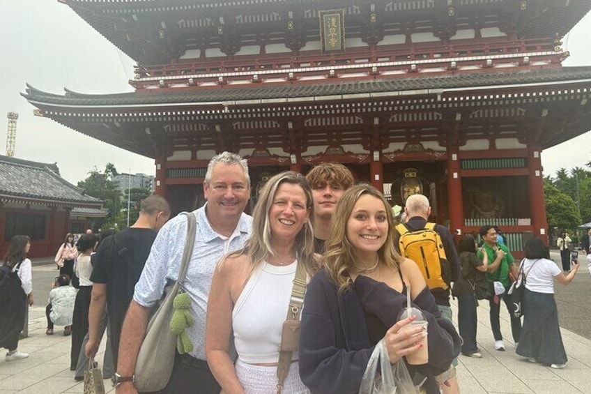 A group of people in front of a traditional Japanese gate with intricate wooden architecture. 5