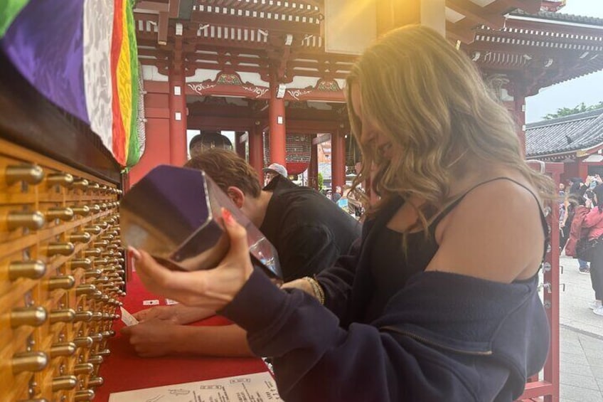 A person taking a photo with a camera at a traditional red pavilion. 4