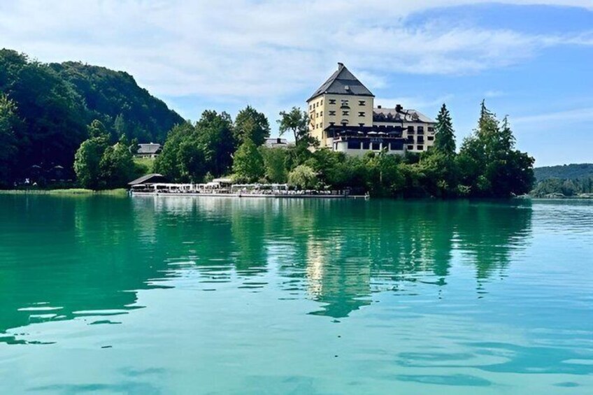 A lake with a castle on an island, surrounded by trees and hills. 5