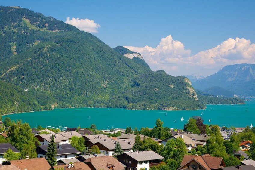 A lake surrounded by mountains, houses near the shore, and sailboats on the water. 3