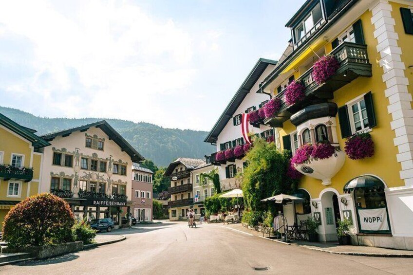 A street with colorful buildings, a sign for 'RAIFLEISENBANK,' and a 'NOPPI' sign. 3