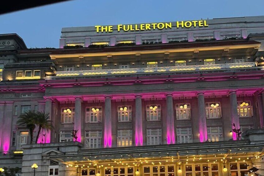 The Fullerton Hotel with illuminated pink and yellow lights, prominent columns, and a classic architectural style. 2