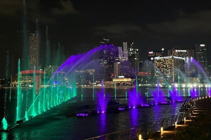 A nighttime cityscape with illuminated fountains and a bridge. 5