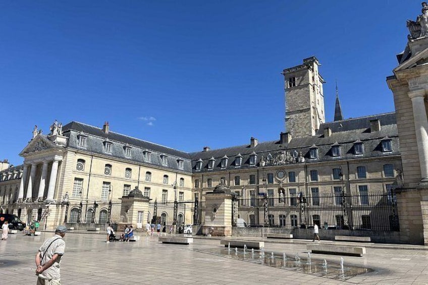 A historic building with a courtyard, a fountain, and a clock tower. 1
