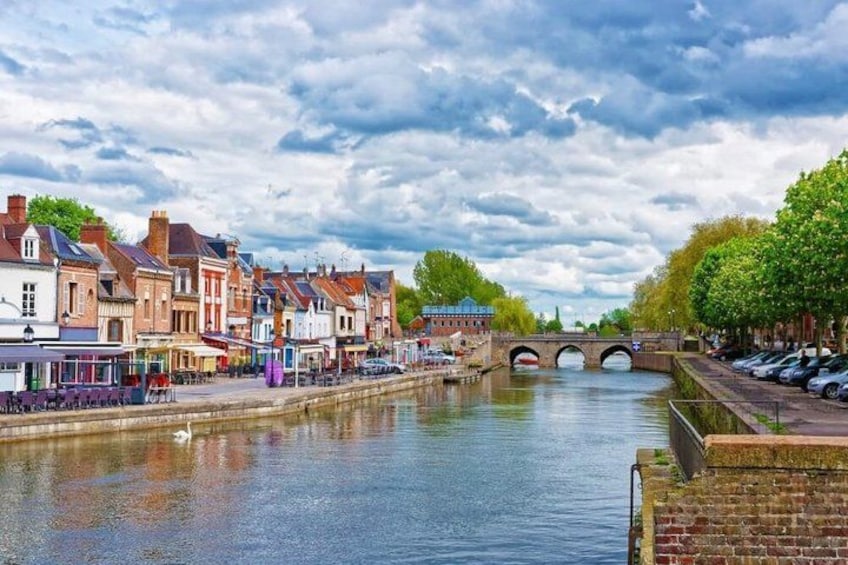 A river with buildings on one side and a bridge in the distance. 3