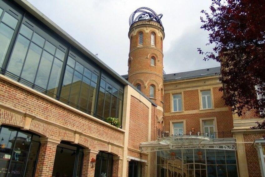 A building with a glass facade, a brick tower, and a glass entrance. 2