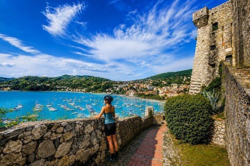 A stone wall, a person, a coastal town, and a clear blue sky. 3