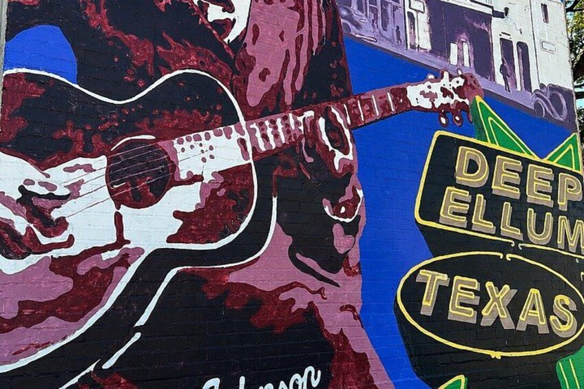 A mural with a guitar, the text 'DEEP ELLUM TEXAS,' and a building in the background. 2