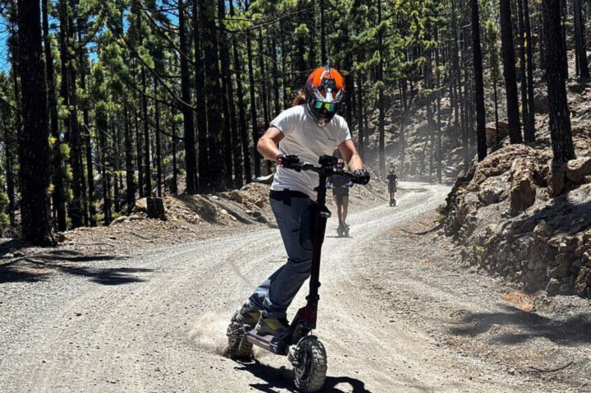 A person riding a mountain bike on a dirt road surrounded by trees. 4