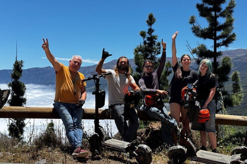 A group of people with cameras and a tripod on a wooden platform overlooking a valley. 5