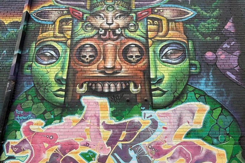 A colorful mural with a central figure and surrounding abstract patterns. 3