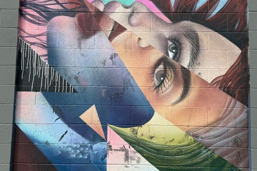 A mural with a woman's face, geometric shapes, and a bridge. 3