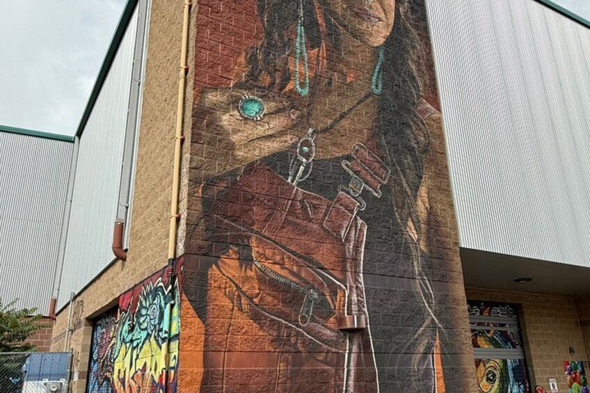 A mural on a building's side, featuring a person with a horse and a large eye. 4
