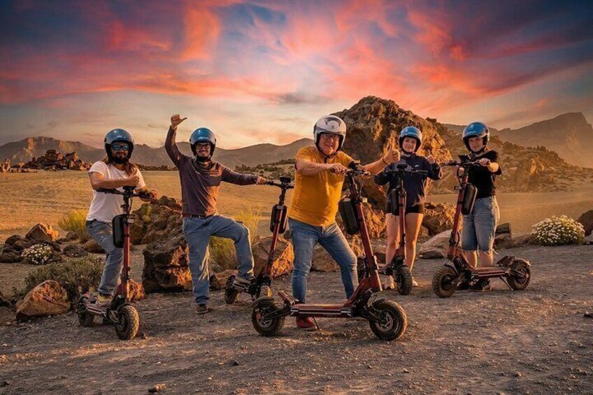 A group of people on electric scooters in a desert landscape with mountains in the background. 1