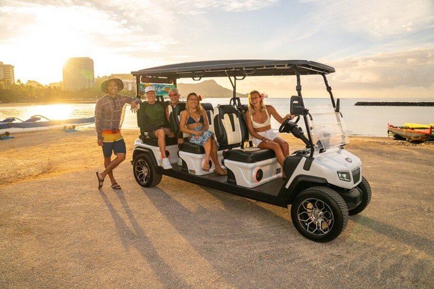 A golf cart with four people on a beach with boats in the background. 4