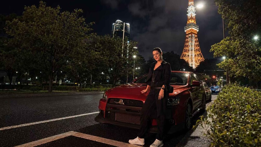 A person standing next to a red car on a street at night with the Eiffel Tower in the background. 5