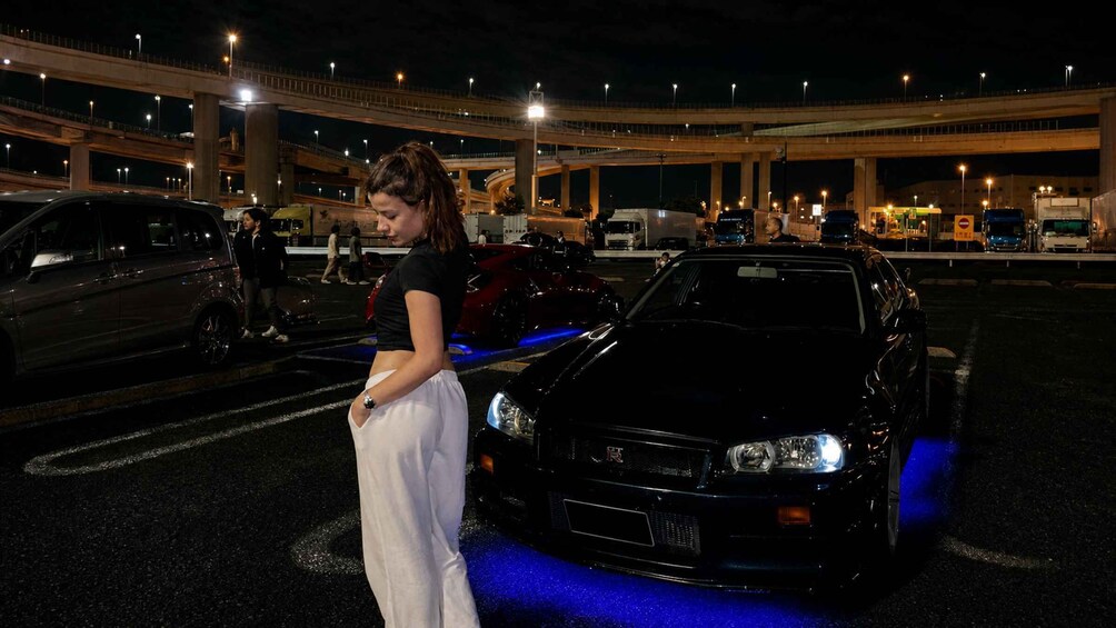 A parking lot with a black car and a pedestrian. 2