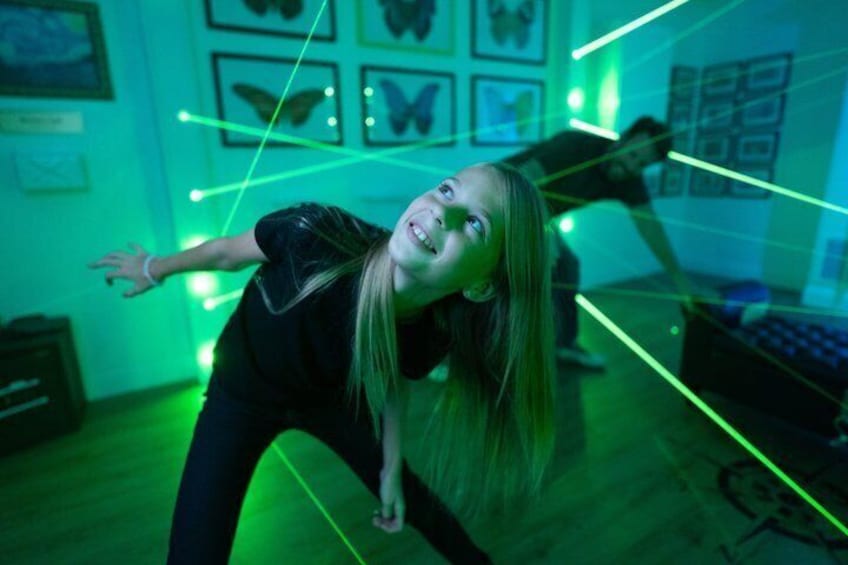 A person bending forward in a room with green laser lights and butterfly wall art. 5