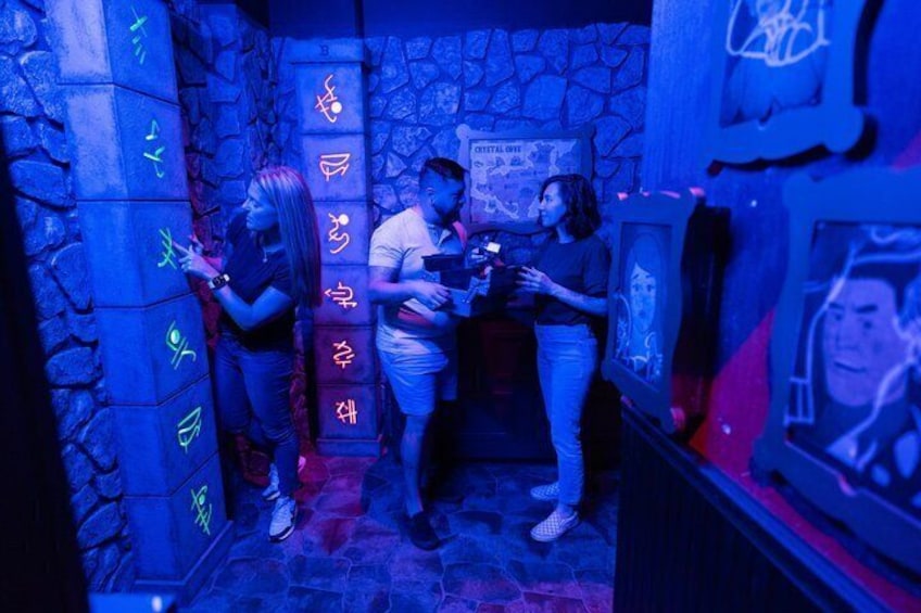 A dimly lit room with stone walls, neon signs, and a poster on the wall. 4