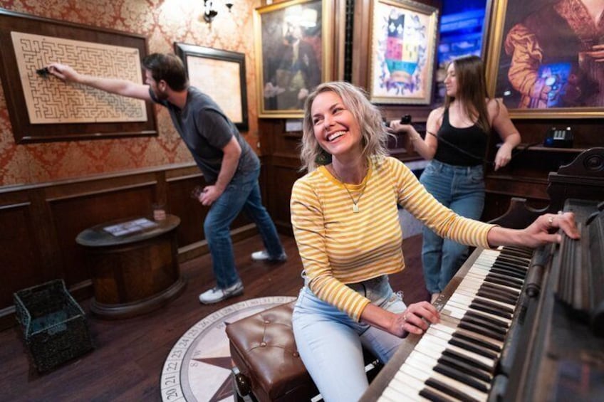 A person playing a piano in a room with wooden walls and framed artwork. 1