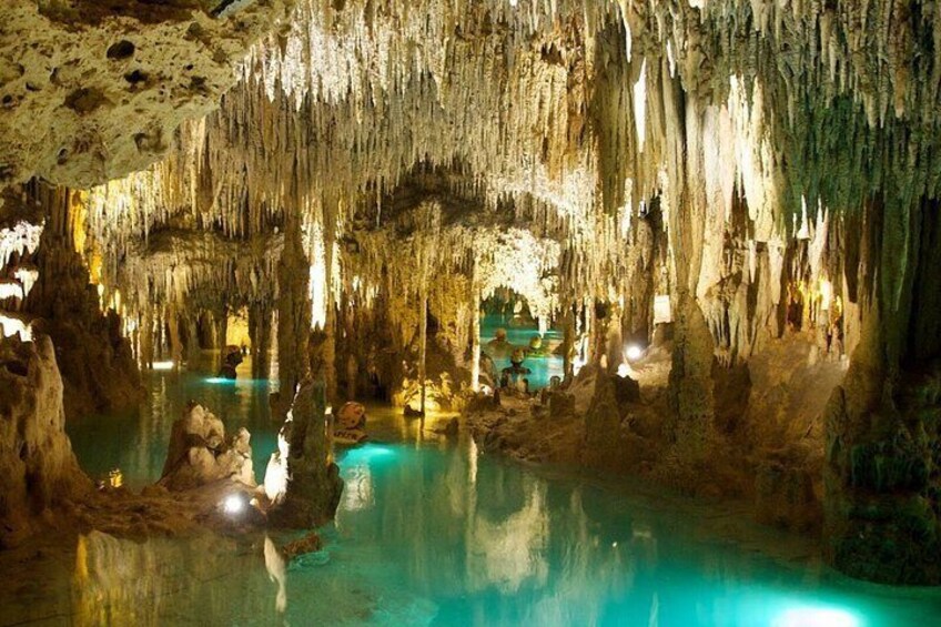 A cave with stalactites, stalagmites, and a pool of water. 3