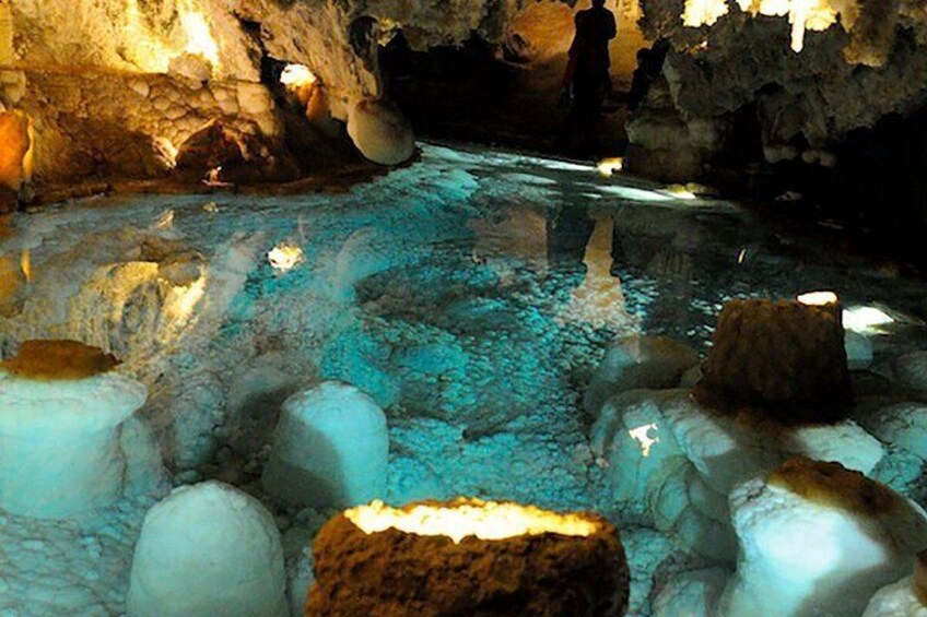 A cave with stalactites, stalagmites, and a water stream. 5