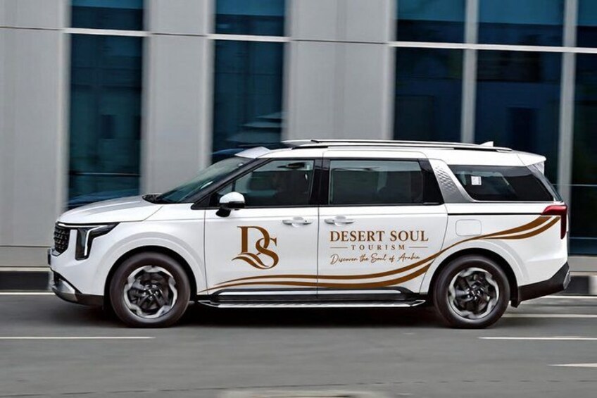 A white SUV with 'Desert Soul Tourism' branding parked in front of a modern building. 4