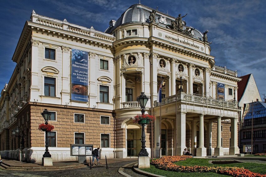 Un edificio histórico con arquitectura ornamentada, una entrada destacada y un cartel que anuncia Slovenská filharmonie. 1