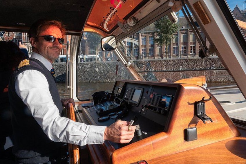 A person steering a boat with a wooden dashboard and a view of a cityscape with buildings and a bridge. 5