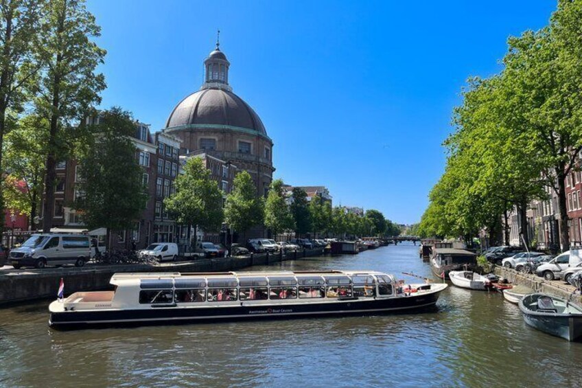 A canal with a boat, a domed building, and trees lining the waterway. 2