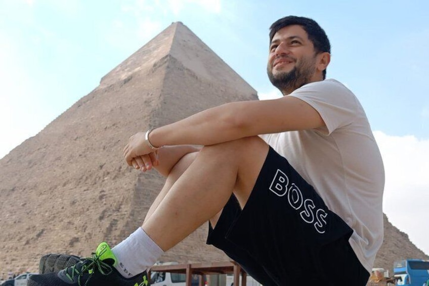 A person sitting with a pyramid in the background. 1