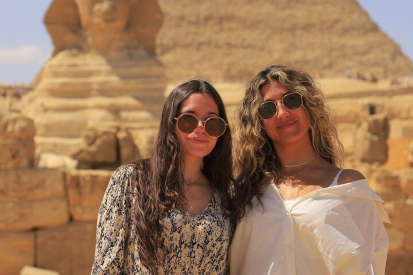Two people standing in front of a large pyramid structure. 3