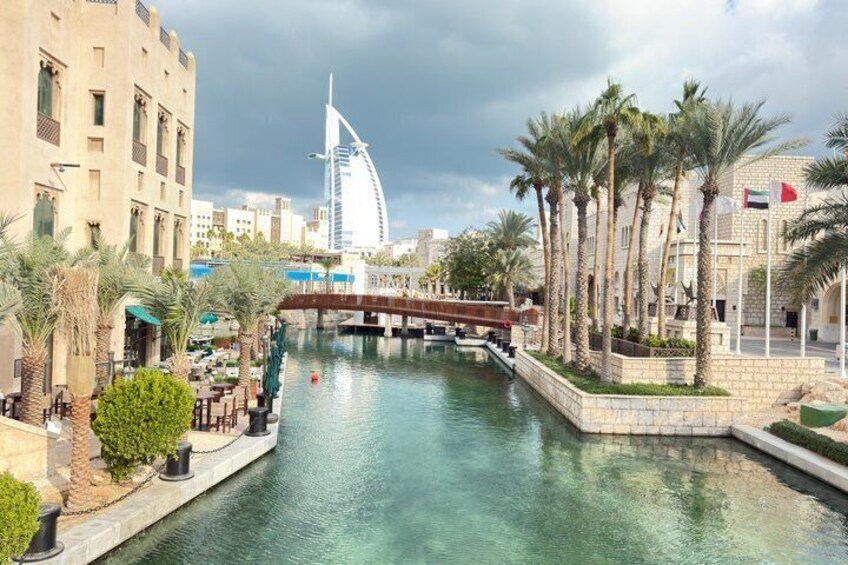 A canal with palm trees, a bridge, and the Burj Al Arab hotel in the background. 5