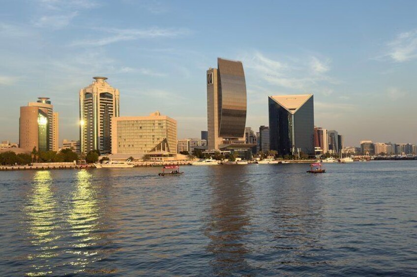 A city skyline with modern buildings and a body of water reflecting the structures. 1