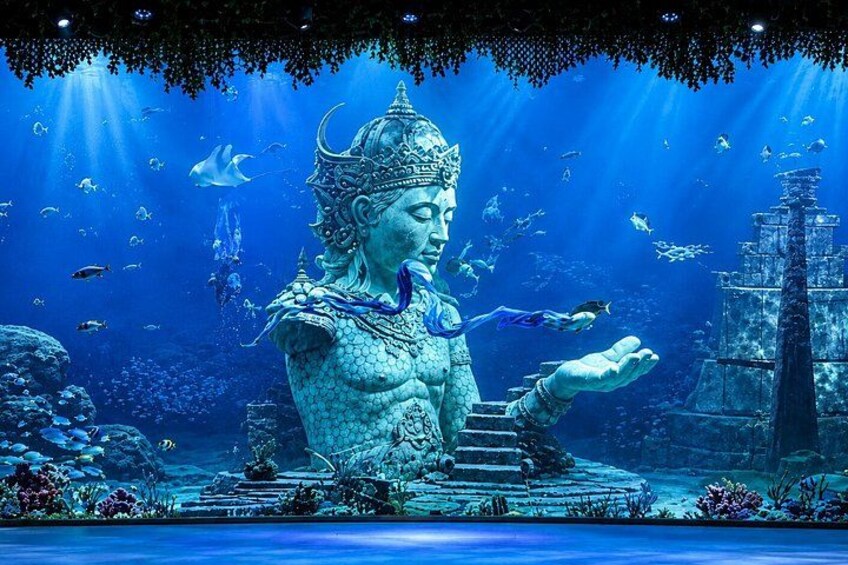 Una estatua imponente de una figura semejante a una sirena, adornada con una corona, rodeada por un paisaje submarino con peces y corales. 1