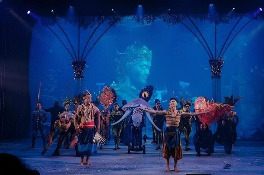 Una función teatral con actores en trajes elaborados sobre un escenario con fondo azul y elementos decorativos. 3