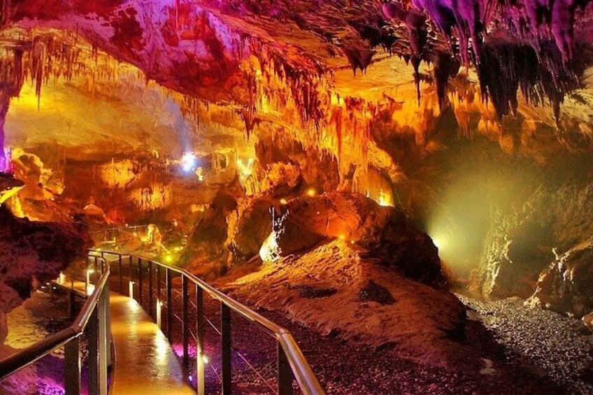 A cave with illuminated stalactites and a metal walkway. 3