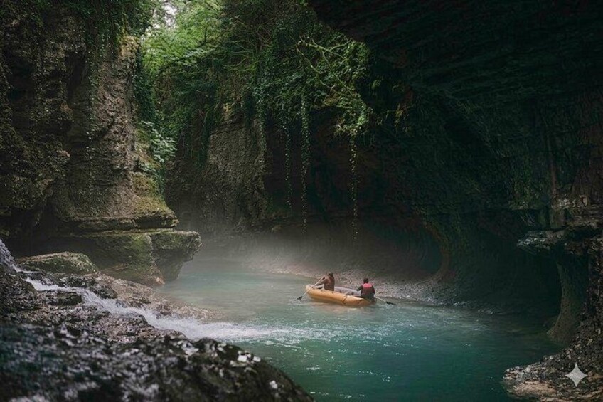A river with a raft, surrounded by rocky cliffs and greenery. 1