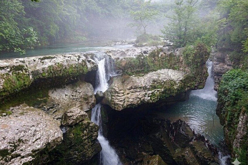 A waterfall cascading over rocky terrain surrounded by lush greenery. 4
