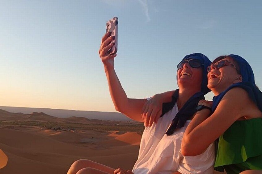 Two people taking a selfie with a desert landscape in the background. 1