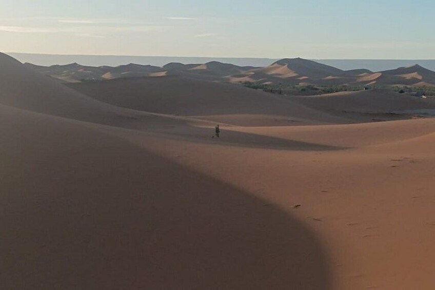 A desert landscape with sand dunes and a person walking. 3
