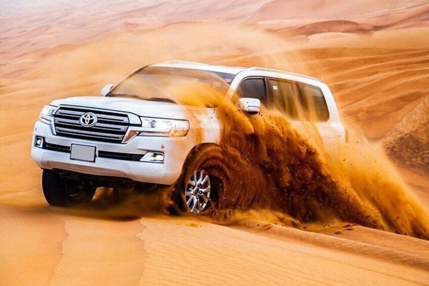 A white SUV driving through a sandy desert landscape. 2