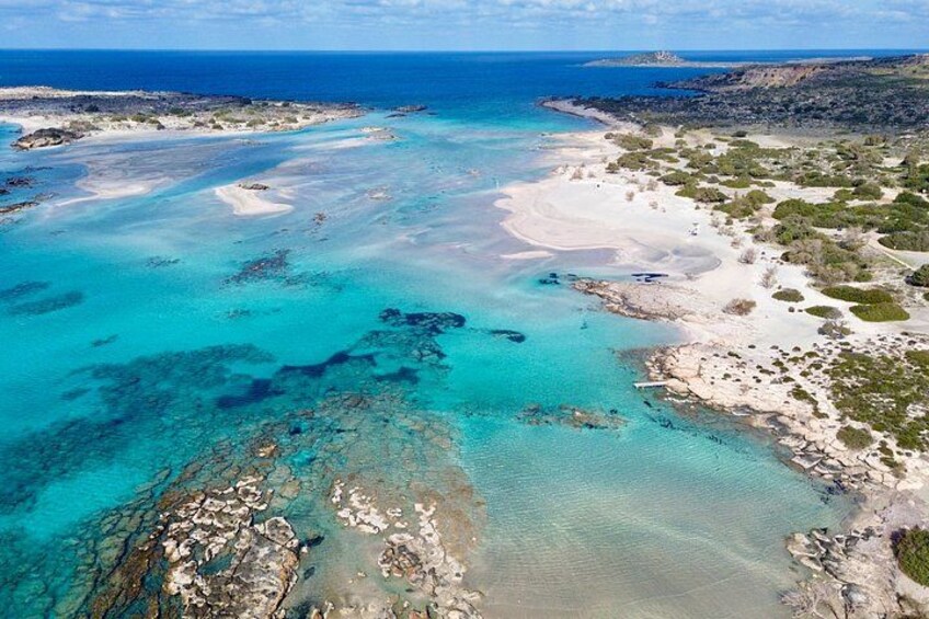 A coastal landscape with clear turquoise waters, sandy beaches, and rocky outcrops. 2