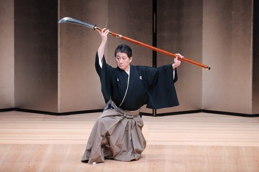 A person in traditional attire holding a sword and a long staff. 3