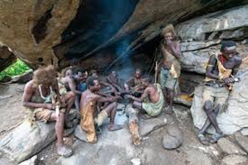 A group of people sitting and standing in a rocky cave. 5