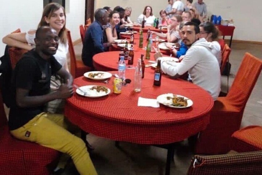 A group of people dining at round tables with red tablecloths. 1