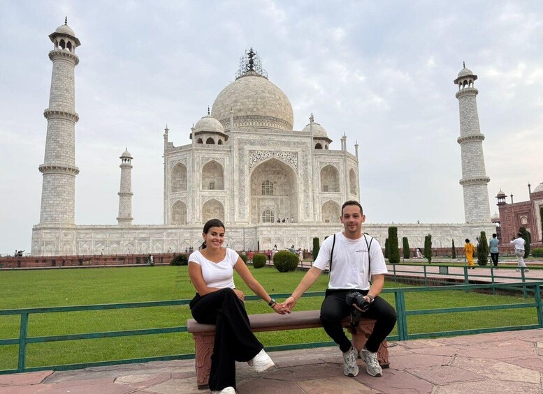 Two people sitting on a bench with the Taj Mahal in the background. 2